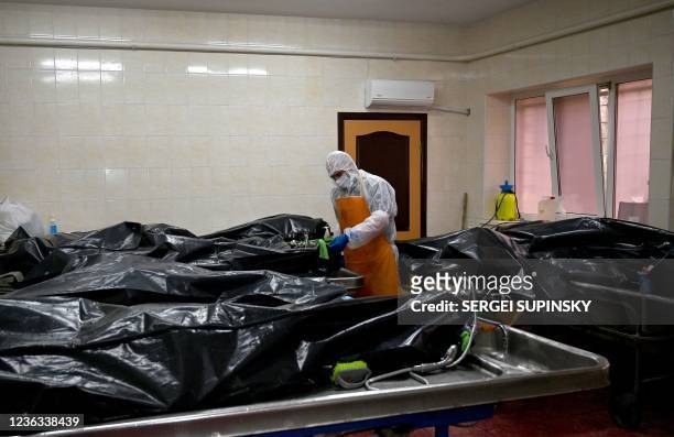 Medical worker checks the name of bodies in black plastic bags in the burial chamber of an hospital which treats patients with COVID-19 coronavirus...