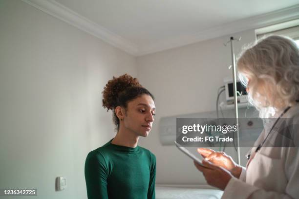 arts die aan patiënt bij het ziekenhuisruimte met digitale tablet spreekt - medical examination room stockfoto's en -beelden