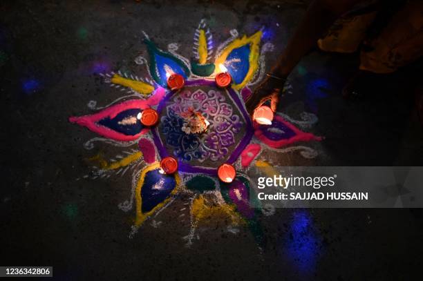 Woman places an oil lamp or "diya" on a rangoli during celebrations for the Hindu festival Diwali or the Festival of Lights in New Delhi on November...