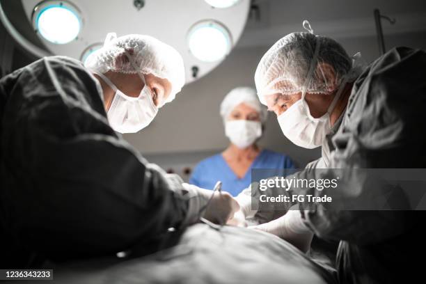 médicos haciendo una cirugía en quirófano en el hospital - transplant surgery fotografías e imágenes de stock