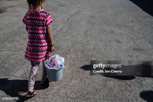Young Afghan girl walks with a bucket of supplies through an Afghan refugee camp on November 4, 2021 in Holloman Air Force Base, New Mexico. The...