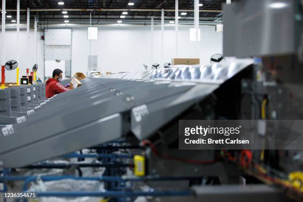 Worker helps operate a Single Induction Parcel Sorter which sorts up to 3,000 machinable parcels per hour during a media tour of a United States...