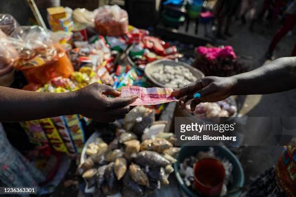 Customer pays with a Ghana cedi banknote at a food market in Accra, Republic of Ghana, on Wednesday, Nov. 3, 2021. Ghanas inflation rate breached the...