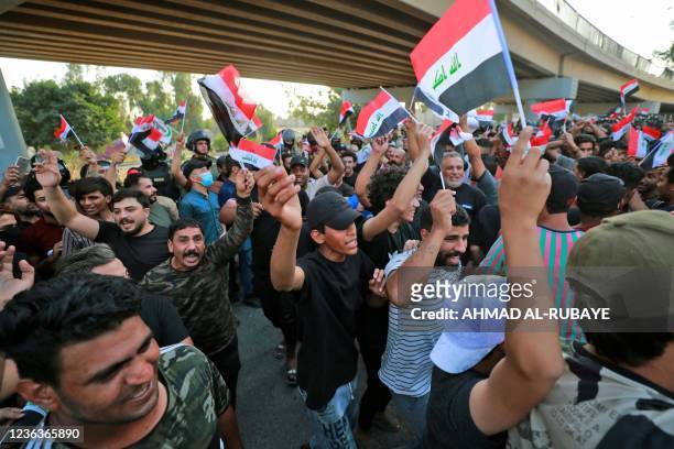 Iraqi protesters lift national flags during a demonstration againt last month's election result, near an entrance to the Green Zone in Baghdad on...