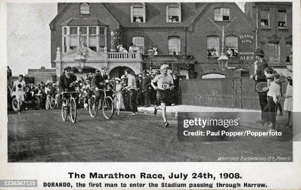 Vintage postcard featuring Italian marathon runner Dorando Pietri running past the Roxborough Hotel in Harrow during London's Summer Olympic Games on...