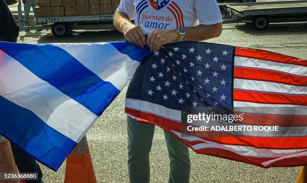Member of the Puentes de Amor NGO holds a Cuban flag and a a US flag, on arrival along with members of The People's Forum and CODEPINK with a cargo...