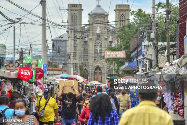 People wearing protective masks walk at a street market in the historic center on November 5, 2021 in San Salvador, El Salvador. Continuing with...