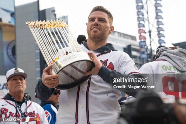 Freddie Freeman holds the Commissioner's Trophy as members of the Atlanta Braves celebrate following their World Series Parade at Truist Park on...