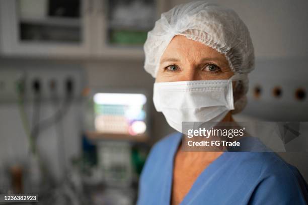porträt einer gesundheitshelferin mit gesichtsmaske im operationssaal im krankenhaus - anästhesist stock-fotos und bilder