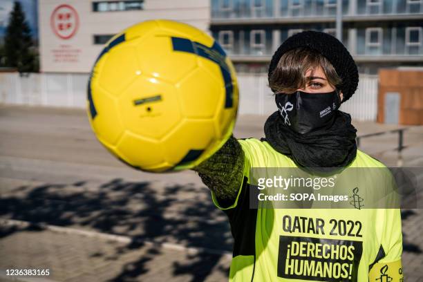 Protester wearing a sports jersey holds a soccer ball, demanding the rights of migrant workers in Qatar during the protest in front of the Spanish...