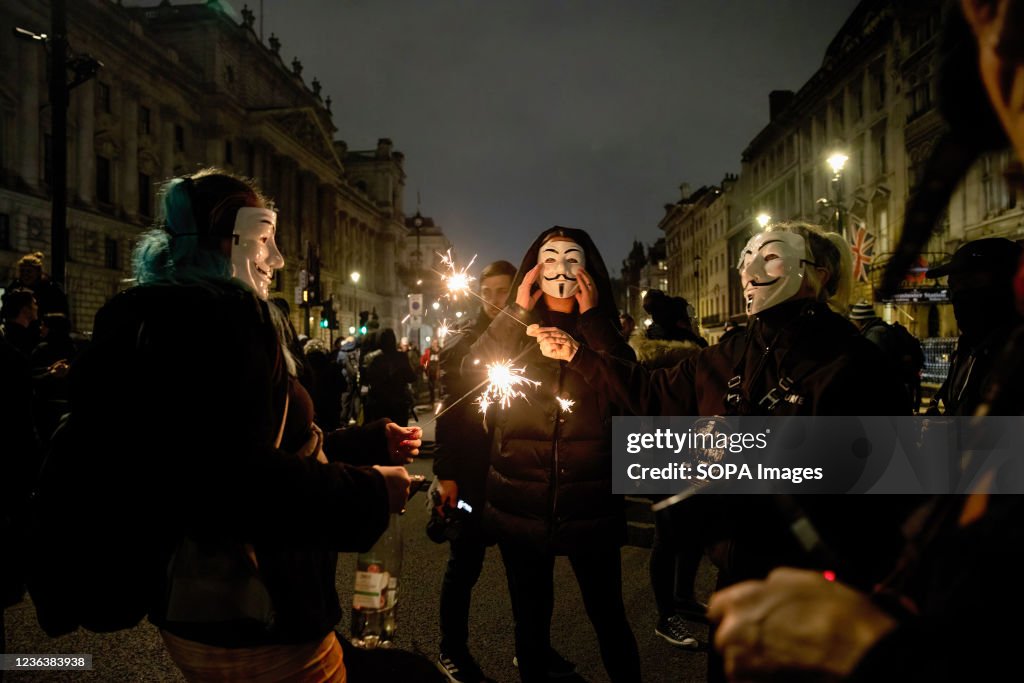 Protesters wearing Guy Fawkes masks light up sparklers...