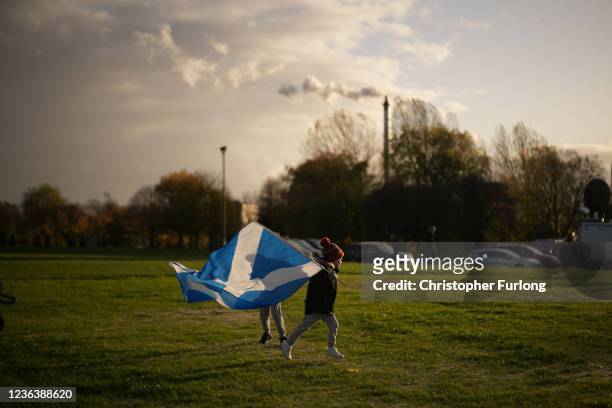 Child runs with a saltire flag as pollution spills from a chimney at Glasgow Green as climate protestors gather for the Global Day of Action for...