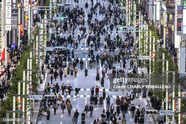 General view shows people walking on a street in Tokyo's Ginza area at dusk on November 7, 2021.