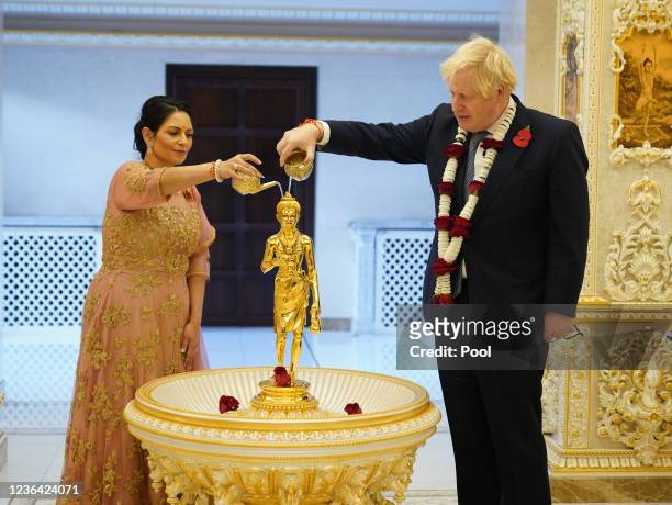 Prime Minister Boris Johnson and Home Secretary Priti Patel pour water over a gilded brass image of Shri Nilkanth Varni in a Abhishek ceremony as...