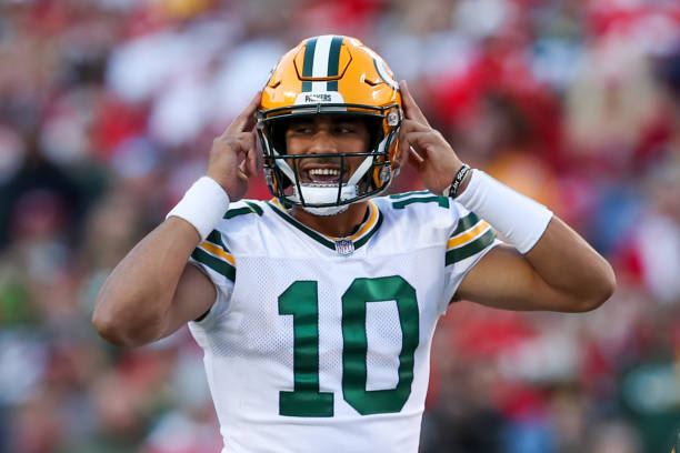 Green Bay Packers quarterback Jordan Love points to his helmet due to crowd noise in the first quarter of an NFL game between the Green Bay Packers...