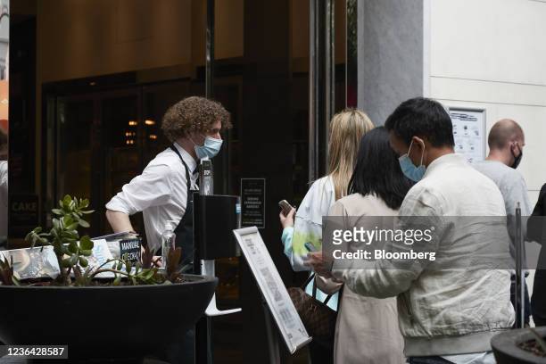Customers wait to enter a cafe in Melbourne, Australia, on Sunday, Nov. 7, 2021. Australian retailers suffered their worst quarter of sales on record...