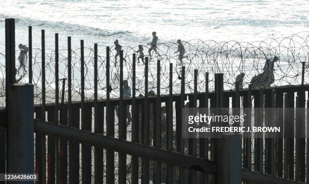 Children play on a beach in Tijuana, Mexico, across the US-Mexico border fence that runs into the Pacific Ocean, seen from Imperial Beach outside San...