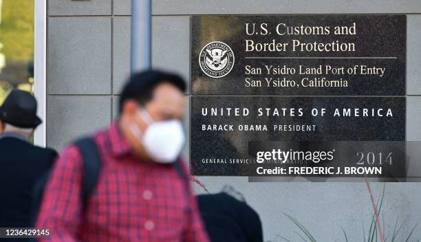 People wear facemasks upon entry into the United States at the San Ysidro Land Port of Entry in San Ysidro, California on November 7 one day before...