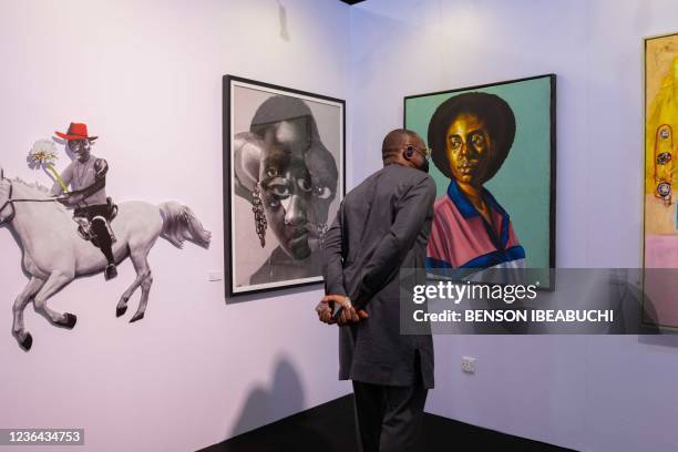 Art enthusiasts look at an artwork by Barry Yusufu titled "Home Girl", at the ArtX annual art fair at the Federal Palace Hotel, Victoria Island, in...