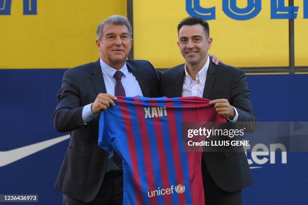 Newly-appointed FC Barcelona's Spanish coach Xavi Hernandez , flanked by FC Barcelona's Spanish president Joan Laporta, poses with his jersey during...