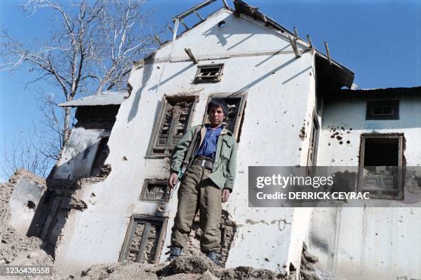 Year-old militiaman stands in front of a destroyed house on January 28, 1987 in Paghman, northwest Kabul, three months after the withdrawal of six...