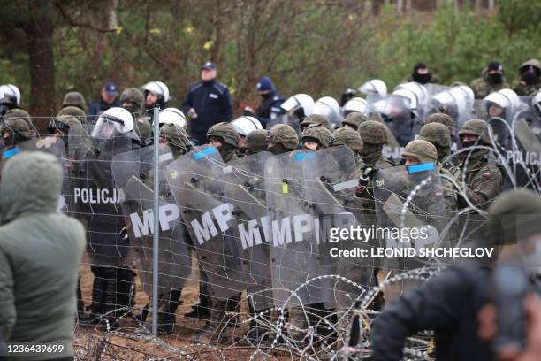 Picture taken on November 8, 2021 shows Poland's law enforcement officers watching migrants at the Belarusian-Polish border. - Poland on November 8...
