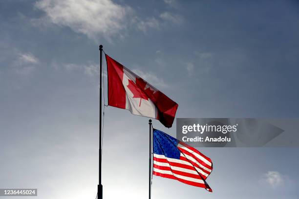 The Canadian and American flags fly above the Peace Arch Border crossing between Canada and the United States, near Seattle, Washington and...