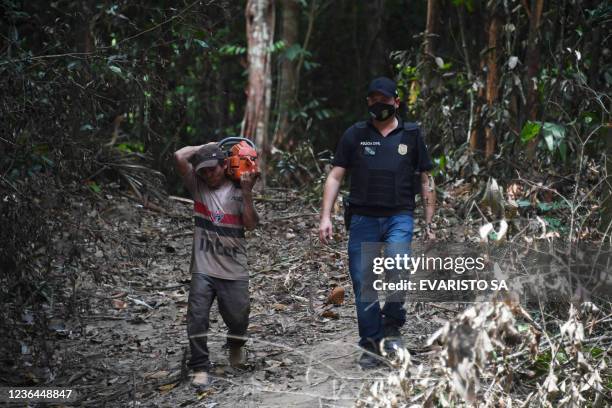 Police officer from Para State, northern Brazil, escorts an illegal logger after arresting him in a camp found during surveillance of areas of the...