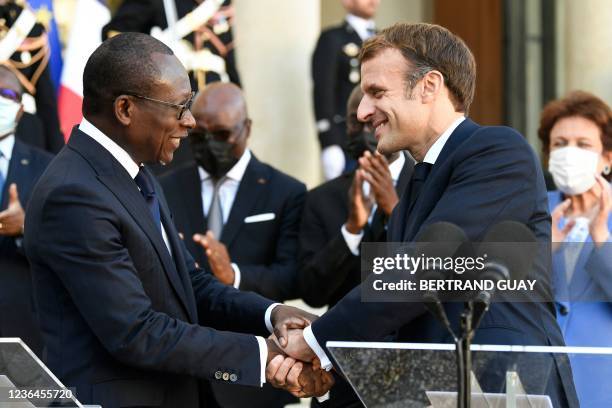 French President Emmanuel Macron holds hands with Benin's President Patrice Talon during a press conference at the Elysee Palace in Paris, on...