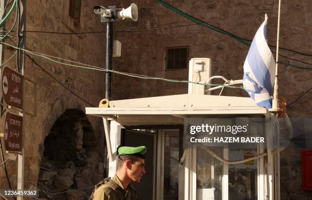 An Israeli soldier stands under a surveillance camera at a checkpoint in the flashpoint Palestinian city of Hebron on November 9, 2021. Israel's army...