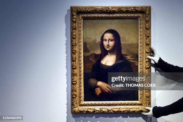 An employee holds up the frame of an original early 19th century replica of the Mona Lisa, in Paris at the Christie's auction house on November 9,...