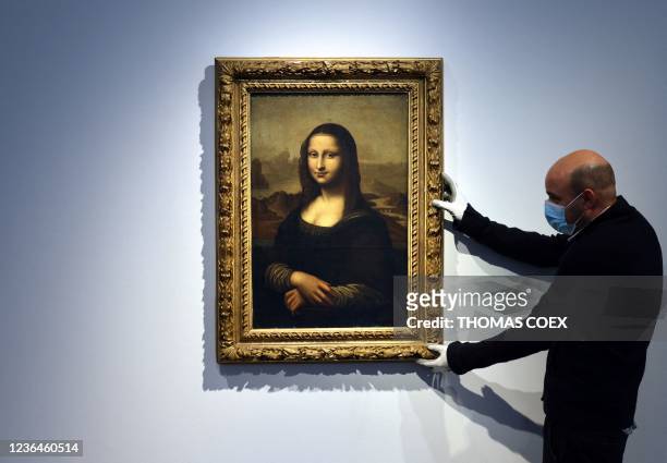 An employee holds up the frame of an original early 19th century replica of the Mona Lisa, in Paris at the Christie's auction house on November 9,...