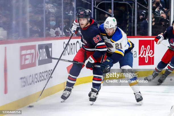 Nikolaj Ehlers of the Winnipeg Jets plays the puck along the boards as Tyler Bozak of the St. Louis Blues gives chase during first period action at...