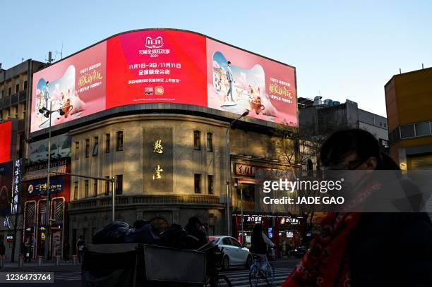 People walk past a billboard promoting the annual "Singles Day" on November 11, the biggest shopping day of the year, at a shopping mall complex in...