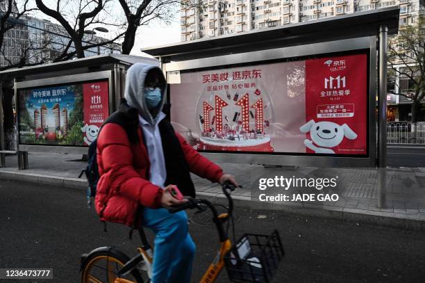 Cyclist rides past billboards promoting the annual "Singles Day" on November 11, the biggest shopping day of the year, at a bus stop in Beijing on...