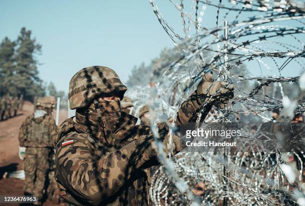 In this handout image issued by the Polish Ministry of National Defence, soldiers from the Polish Armed Forces patrol the Belarus-Polish border on...