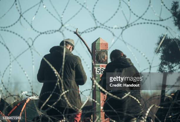In this handout image issued by the Polish Ministry of National Defence, migrants are seen behind barbed wire on the Belarus-Polish border on...