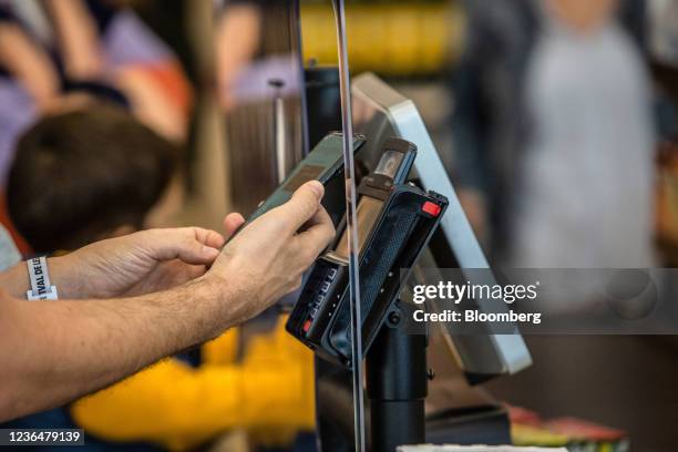 Customer uses their smartphone at a contactless payment terminal on a check-out till inside a Mercadona SA supermarket in Valencia, Spain, on...