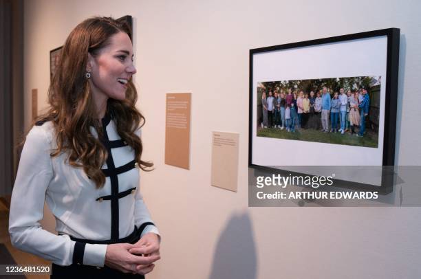 Britain's Catherine, Duchess of Cambridge looks at a photograph of Ziggi Shipper and his family by photographer Arthur Edwards during a visit to the...