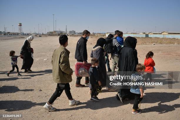 In this picture taken on October 19, 2021 Afghans who were forcibly sent back from Iran to Afghanistan walk towards the border between Afghanistan...