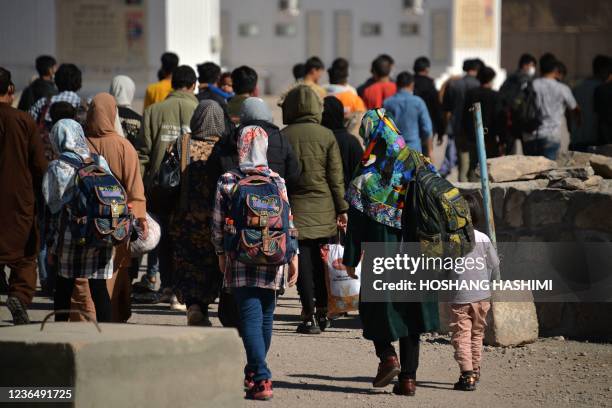 In this picture taken on October 19, 2021 Afghans who were forcibly deported back from Iran to Afghanistan walk towards the border between...