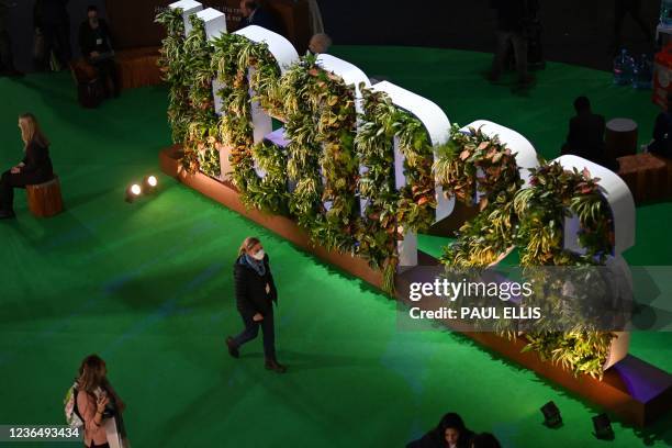 Woman walks past a COP26 sign covered with plants inside the Action Hub during the COP26 UN Climate Change Conference in Glasgow on November 11,...