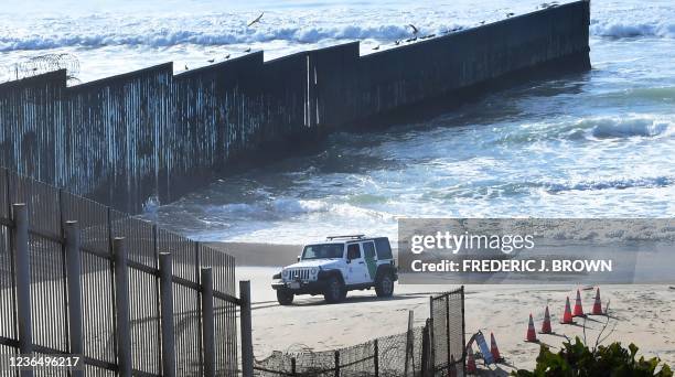 Border Patrol vehicle drives past the US-Mexico border fence which runs into the Pacific Ocean near Friendship Park in Imperial Beach, California on...