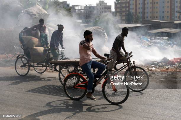 People make their move as garbage fire creates toxic smoke beside a road near the old Buriganga river channel at the Keraniganj area in Dhaka,...