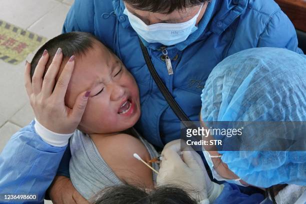Child reacts as he is vaccinated against the Covid-19 coronavirus in Yantai, in China's eastern Shandong province on November 11, 2021. - China OUT /...