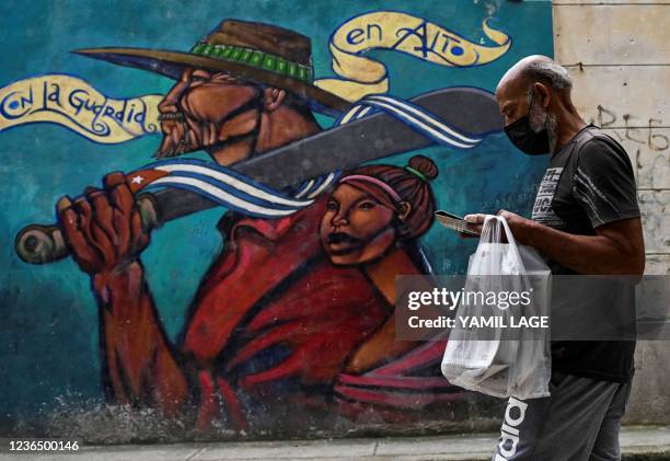 Man wearing a face mask walks past a graffiti in Havana, on November 11, 2021.