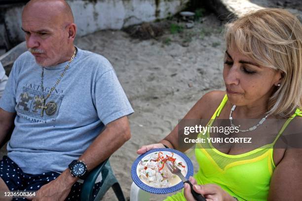 Tourists eat ceviche prepared with lionfish by fisherman William Alvarez on the bach of Chichiviriche de la Costa, Vargas state, Venezuela, on...