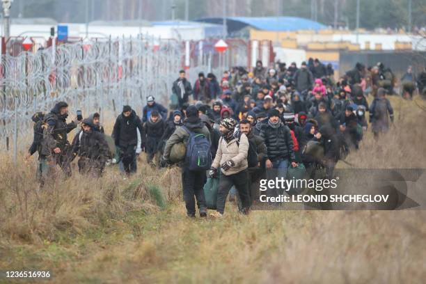 Group of migrants moves along the Belarusian-Polish border towards a camp to join those gathered at the spot and aiming to enter EU member Poland, in...