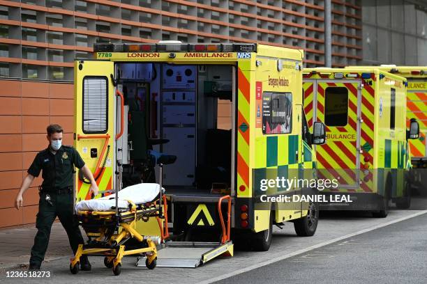 Paramedic wheels a stretcher off an ambulance outside the Royal London Hospital in east London on November 12, 2021. - All frontline workers in the...