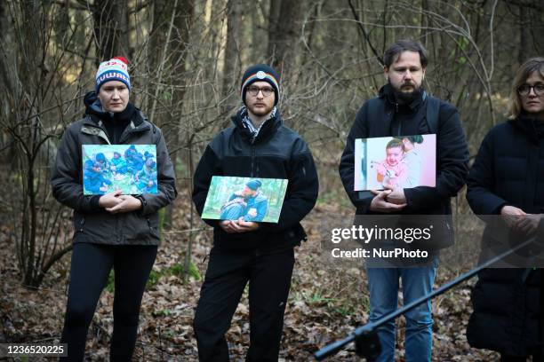 Activists hold photos of migrants found near the border during a press conference near Kuznica, Poland on 12 November, 2021. In a location close to...